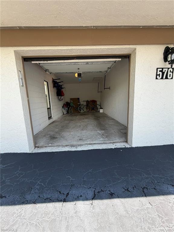 Single-car garage with a concrete floor, automatic door opener, and interior lighting