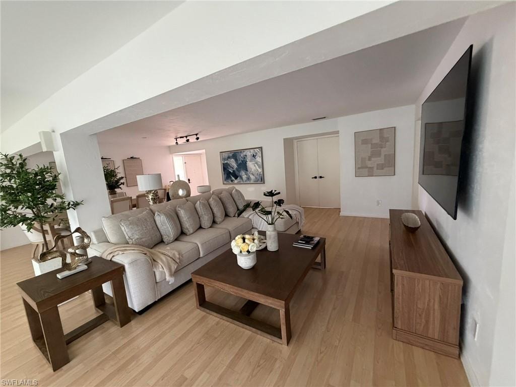 Light wood-finish flooring extending through the primary living space, featuring recessed lighting and a white wall palette