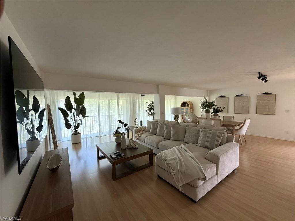 Spacious living area featuring light wood-finish flooring, ample natural light from extensive window walls, recessed lighting, and an open-concept layout