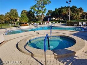 Resort-style pool area featuring a circular spa, multiple swimming pools with blue tile accents, and extensive patterned concrete decking