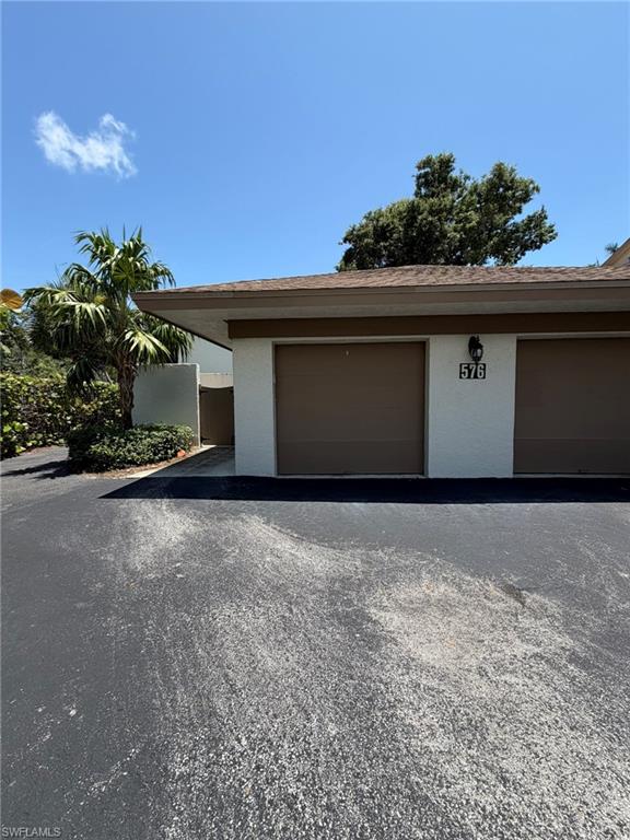 Exterior featuring one garage door, stucco siding, and a partial roofline
