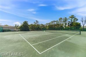 Outdoor tennis court featuring a hard court surface, white line markings, and a dark net