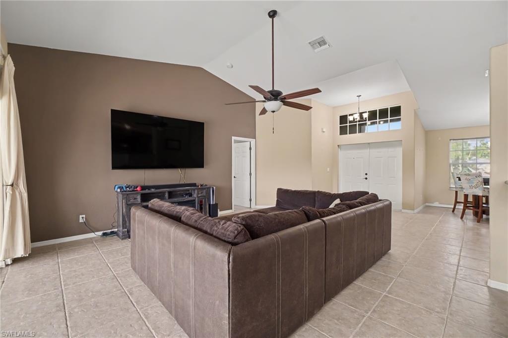 Spacious living area featuring vaulted ceilings, tile flooring, and a ceiling fan