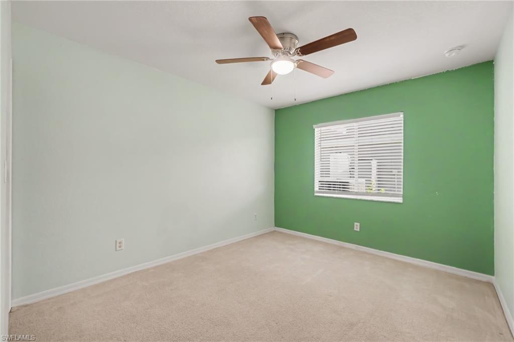 Carpeted room featuring a ceiling fan with integrated lighting, a window with horizontal blinds, and a contrasting accent wall