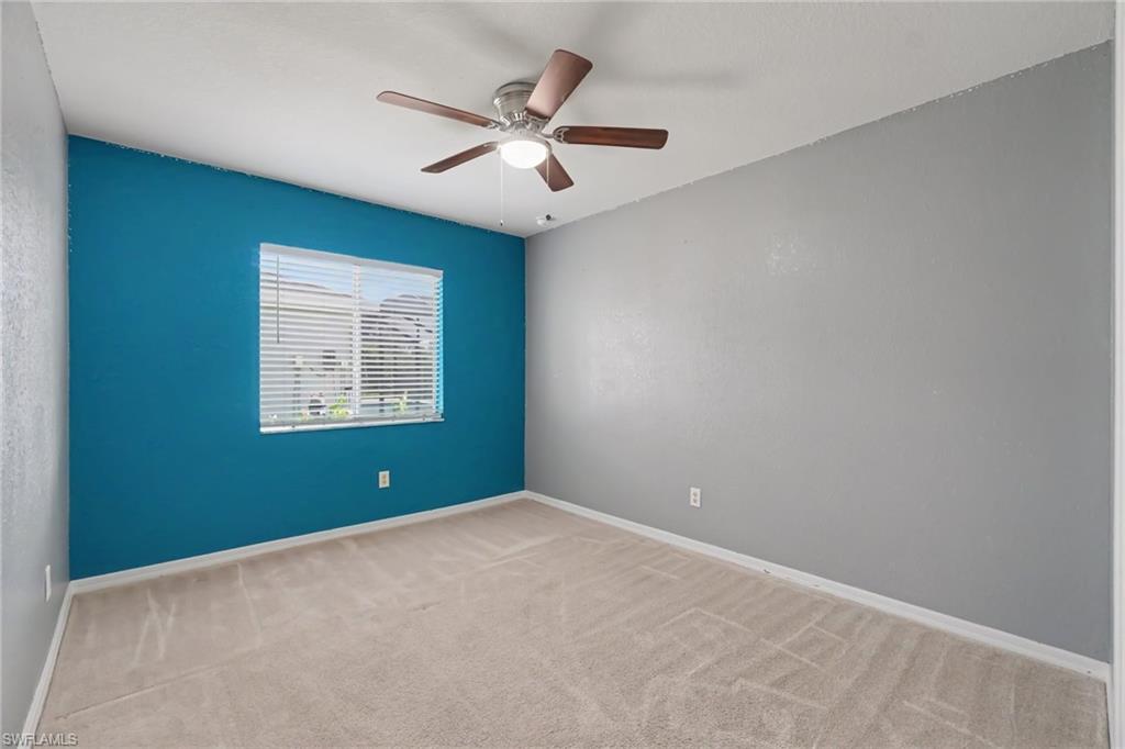 Room featuring a window with white blinds, a ceiling fan with light fixture, light neutral-toned carpet, and a blue accent wall