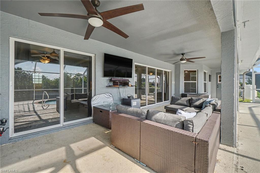 Spacious covered patio featuring multiple ceiling fans, recessed lighting, and direct access to the screened pool area through glass sliding doors