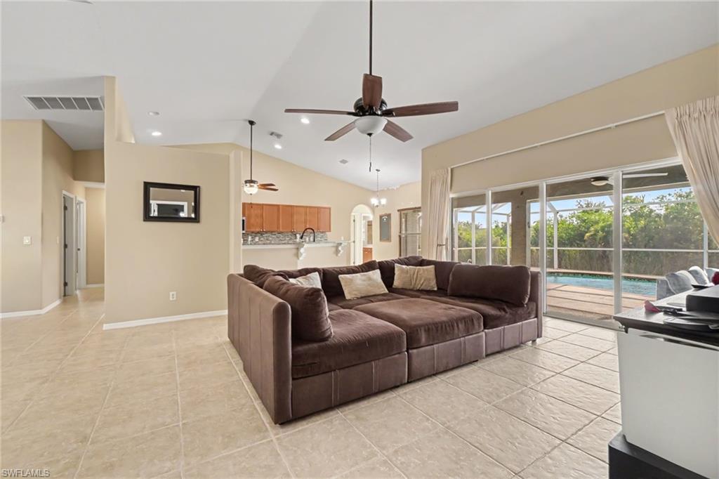 Spacious living area featuring neutral tile flooring and vaulted ceilings