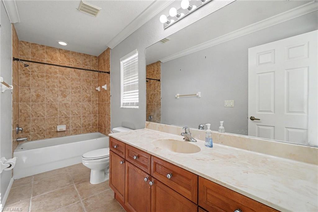 Bathroom featuring a vanity with wood-finish cabinetry, a light-colored countertop, and a spacious mirror