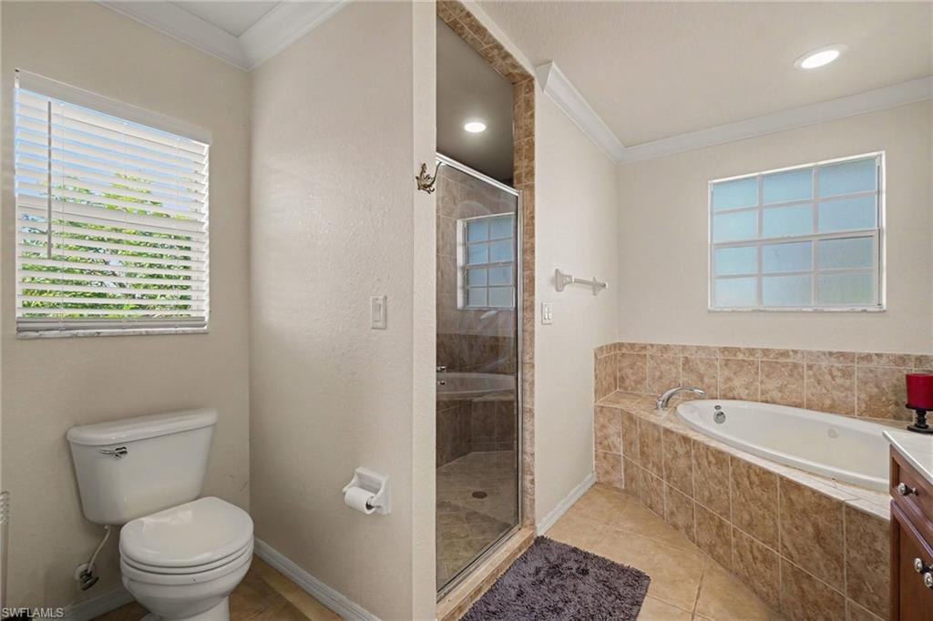 Spacious bathroom featuring a tile-surround soaking tub, glass-enclosed shower, and coordinating floor tiling