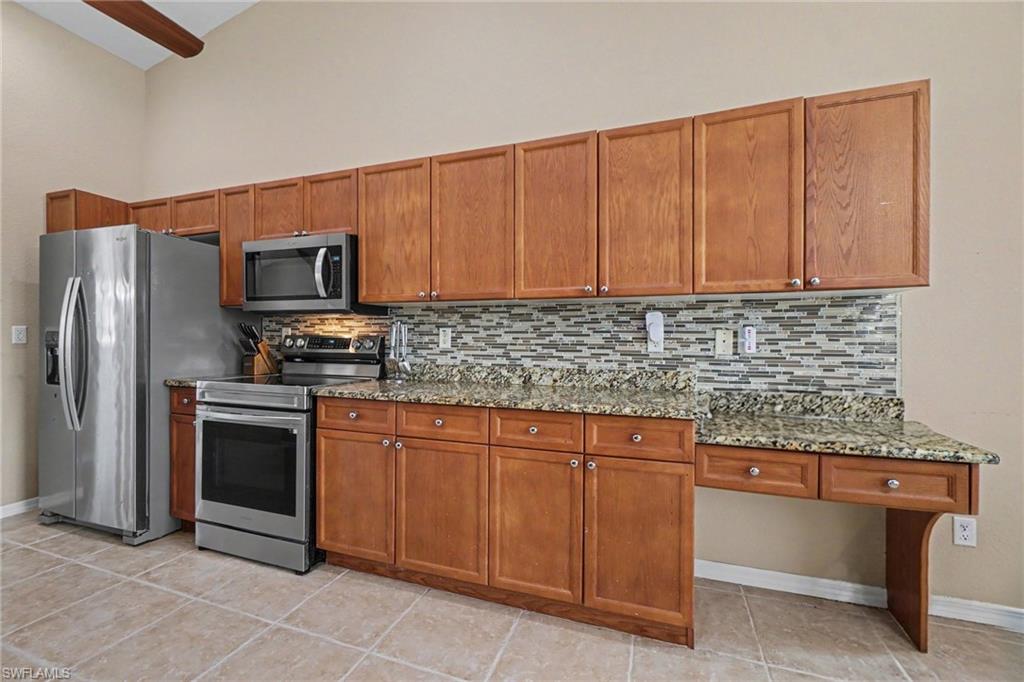 Kitchen featuring wood cabinetry, stainless steel appliances, granite countertops, and a tiled backsplash