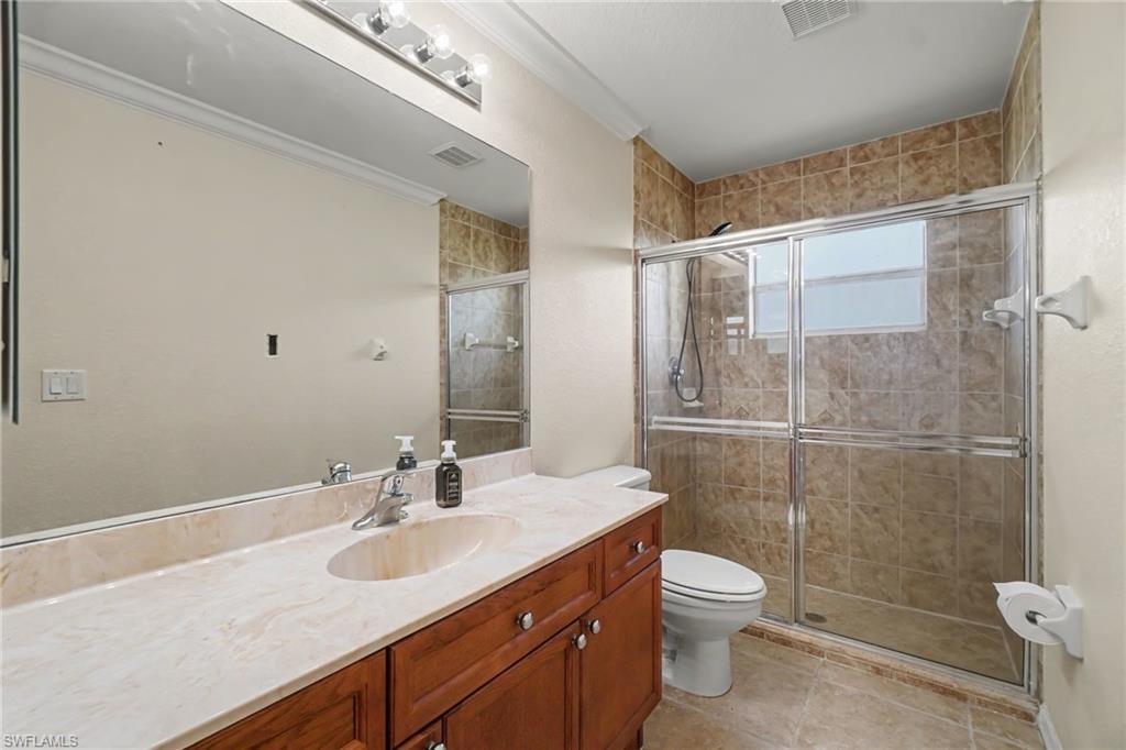 Bathroom featuring a single vanity with wood-finish cabinetry, a light-toned countertop, and an integrated sink