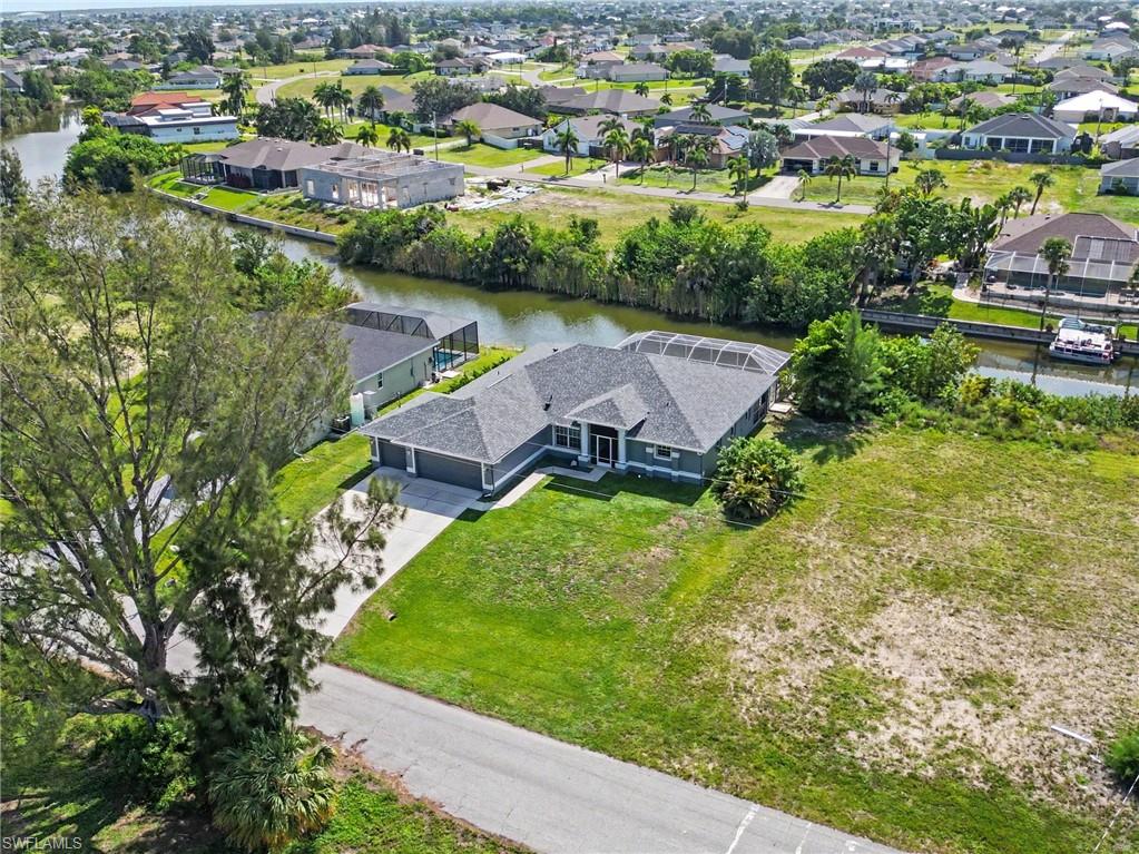 Waterfront property featuring a dark-toned exterior with a screened lanai, a two-car garage, and a concrete driveway