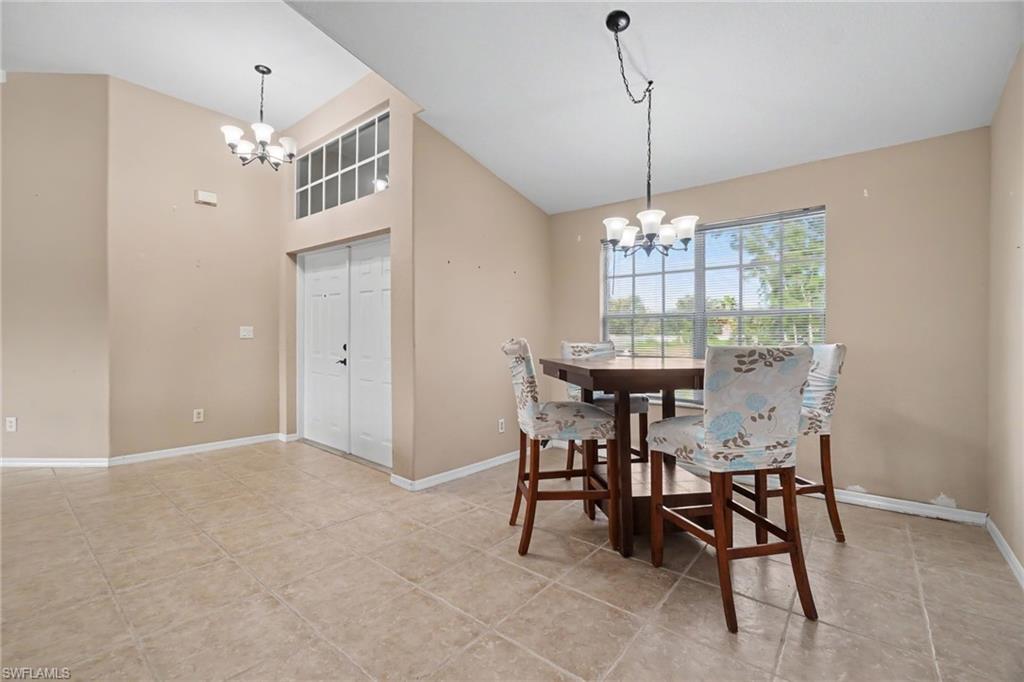 Tiled flooring throughout with vaulted ceilings, transom window above double entry doors, and a chandelier lighting fixture