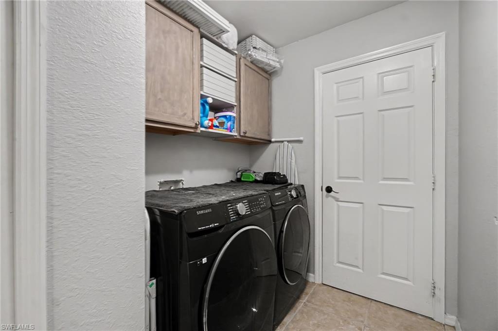 Laundry area featuring built-in upper cabinetry, tiled flooring, and a paneled door