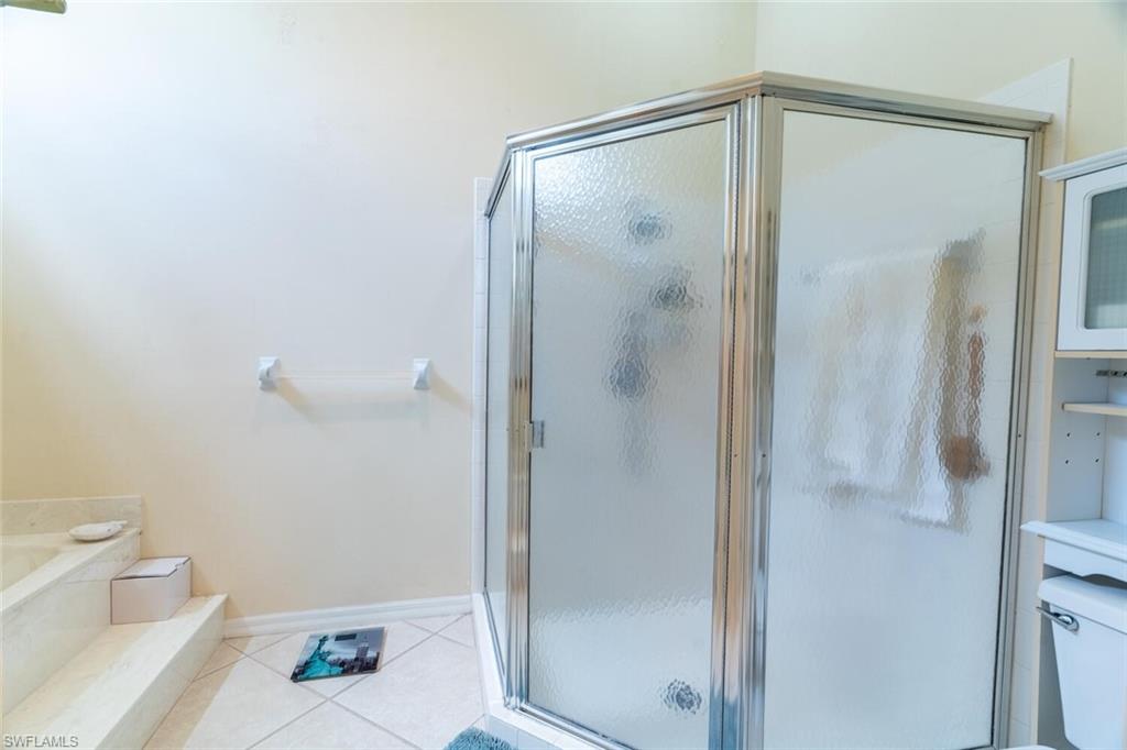 Bathroom featuring light tile patterned floors, a shower stall, and a garden tub