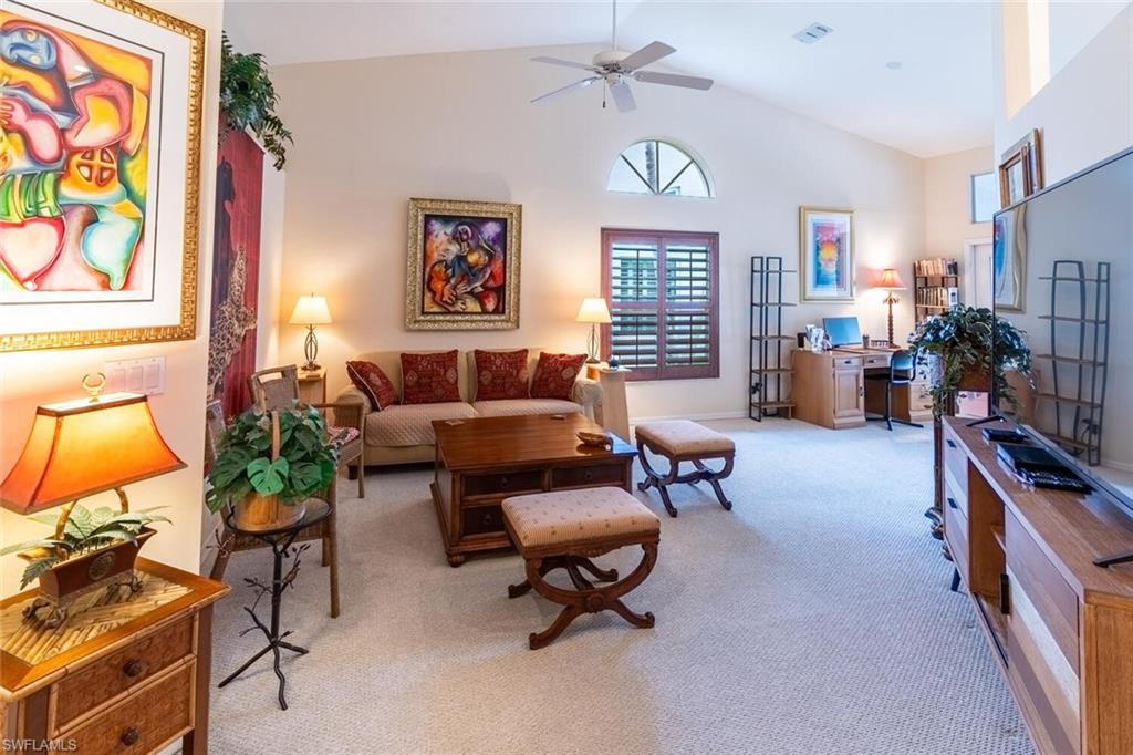 Living area featuring light carpet, high vaulted ceiling, and ceiling fan