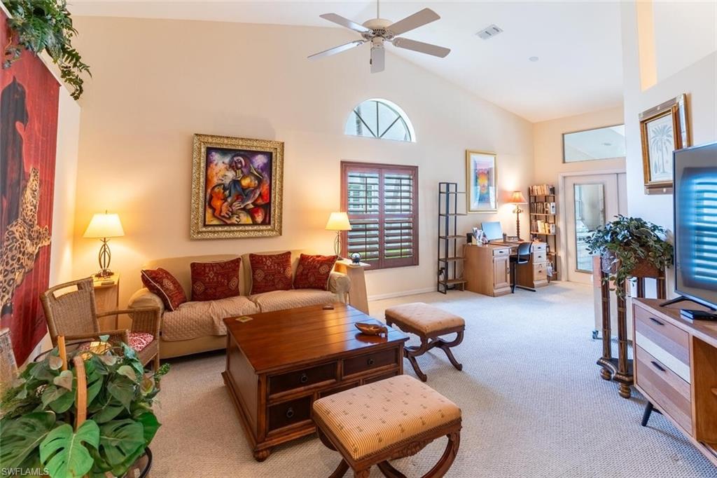 Living area featuring carpet floors, high vaulted ceiling, and a ceiling fan