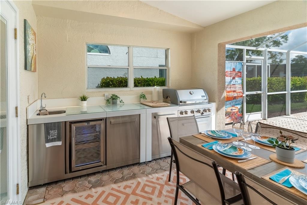Kitchen with a textured wall, light countertops, beverage cooler, vaulted ceiling, and plenty of natural light
