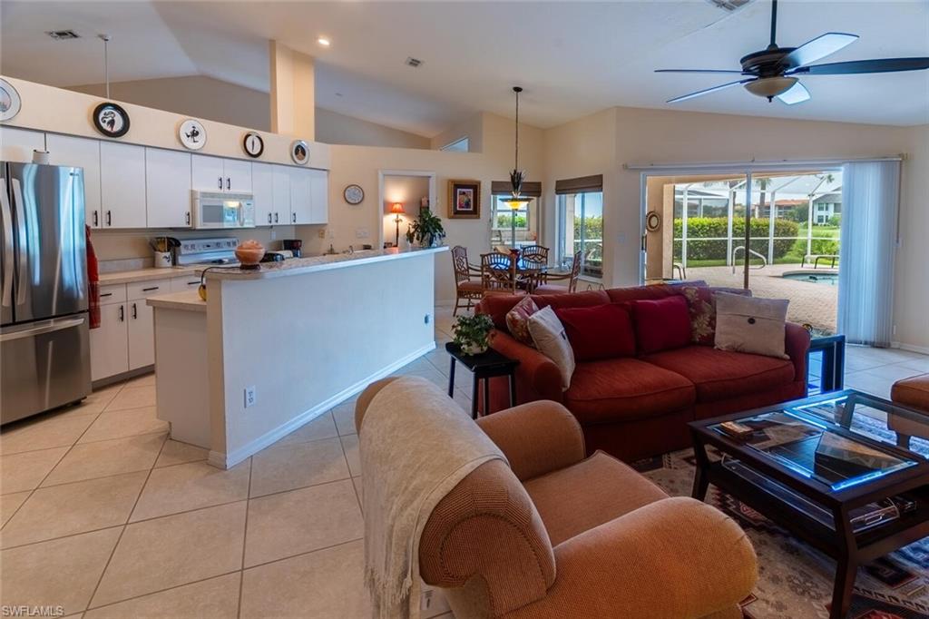 Living area with vaulted ceiling, light tile patterned floors, and ceiling fan