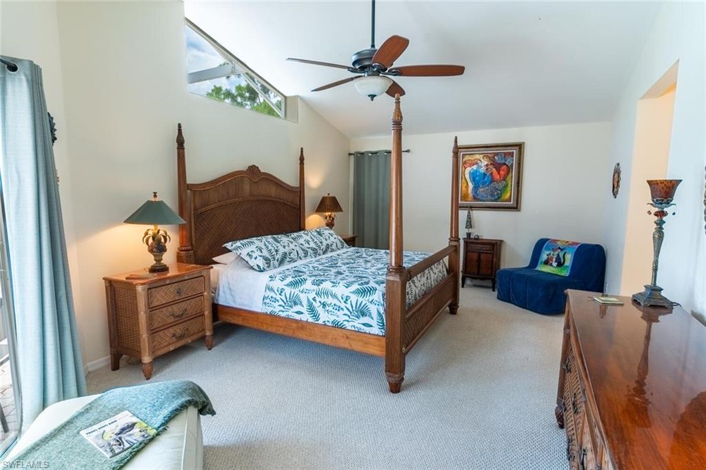 Carpeted bedroom with ceiling fan and high vaulted ceiling