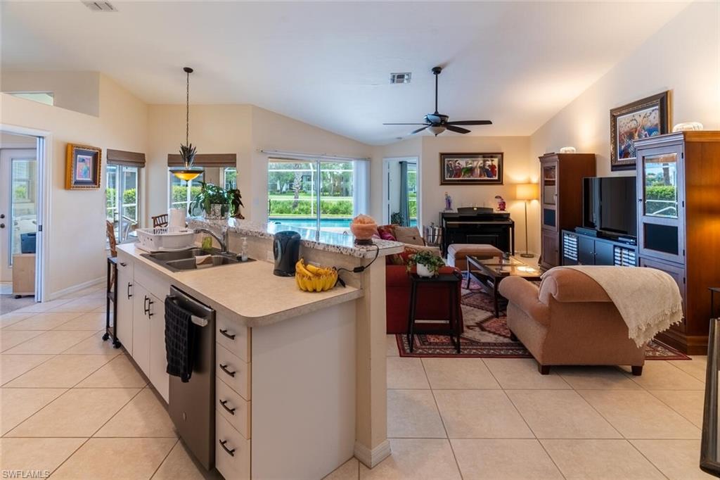 Kitchen with vaulted ceiling, pendant lighting, light tile patterned flooring, white cabinets, and light countertops