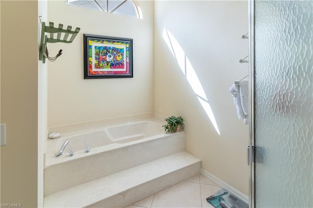 Bathroom featuring a garden tub, tile patterned flooring, and a shower stall