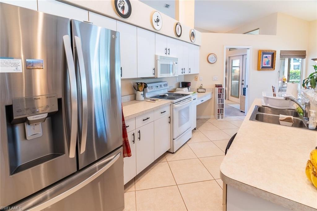 Kitchen featuring white appliances, white cabinetry, light countertops, and light tile patterned floors
