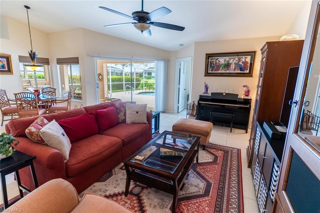 Living room featuring light tile patterned floors, lofted ceiling, and ceiling fan