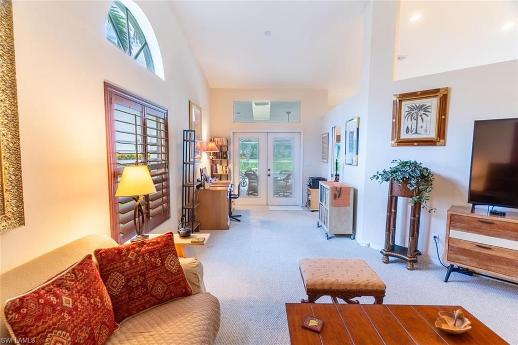 Carpeted living room featuring french doors and a high ceiling