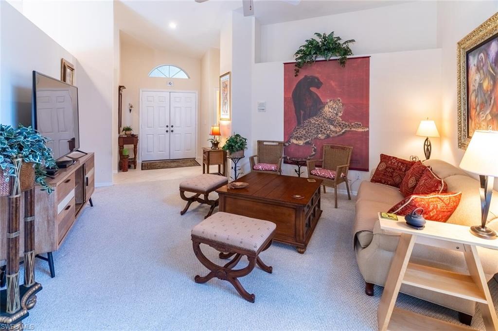 Living room with a high ceiling, light carpet, and ceiling fan