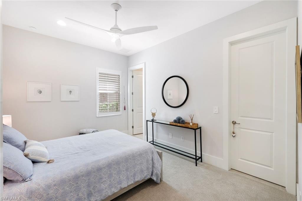 Carpeted room featuring a ceiling fan, a window with horizontal blinds, and a white paneled door with brushed nickel hardware
