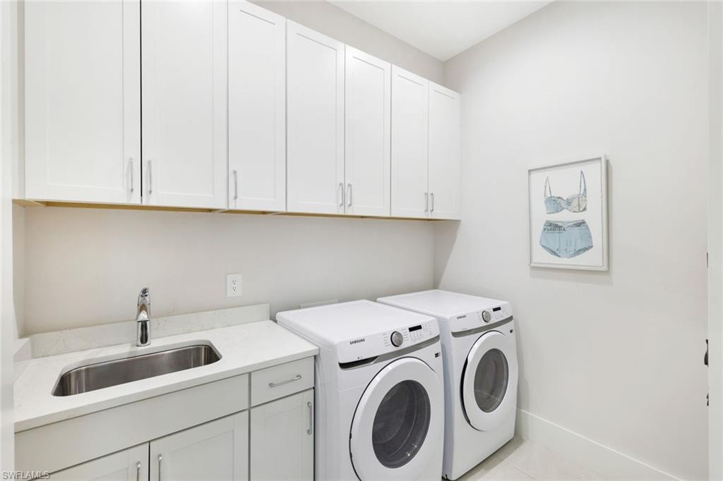 Laundry room featuring white cabinetry, a built-in sink with a chrome faucet, a light-toned countertop, and two large appliance spaces