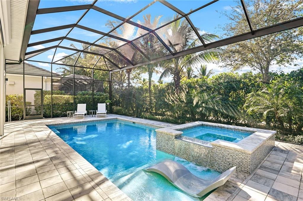 Screened-in outdoor living space featuring a swimming pool, integrated spa with mosaic tile, and a built-in sun shelf