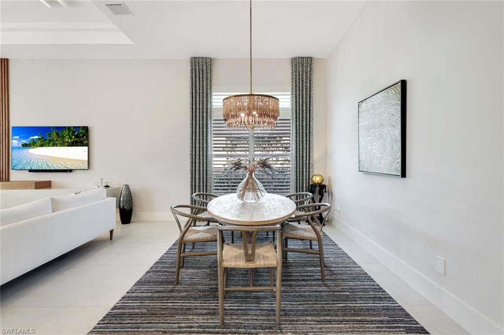 Dining area featuring a contemporary chandelier, large window with horizontal blinds, and patterned drapes