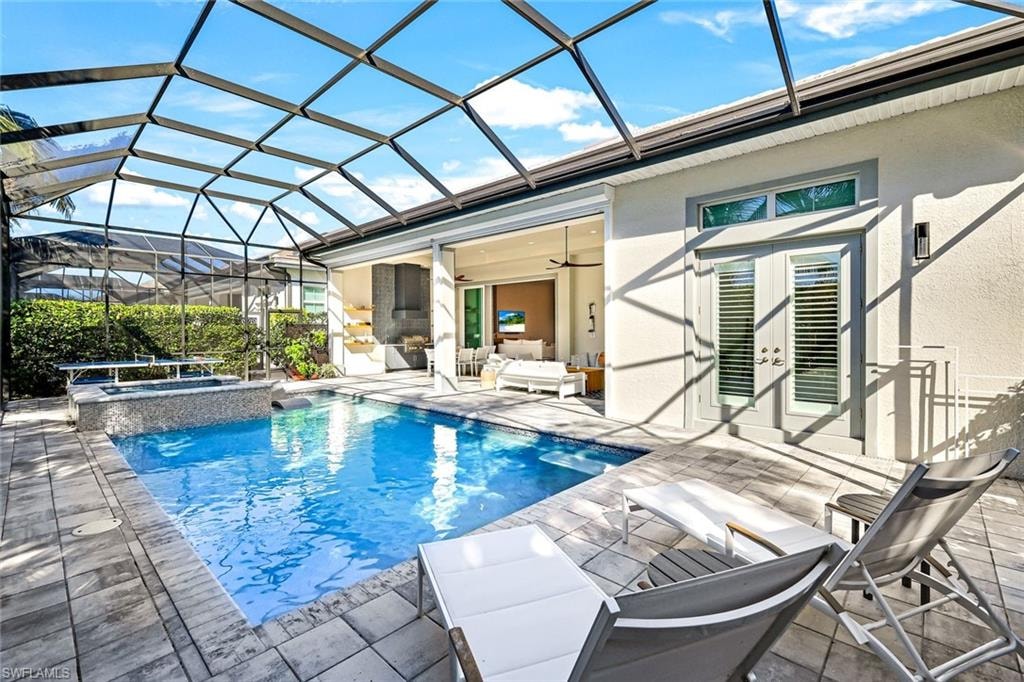 Screened lanai featuring a swimming pool and integrated spa, paver patio, and stucco exterior with french doors and transom windows