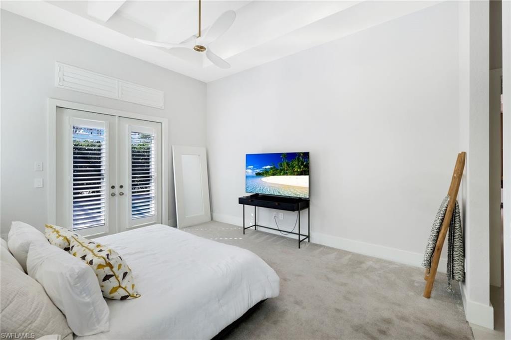 Recessed ceiling with a central fan, light-colored carpeting, white walls, and French doors with louvered shutters