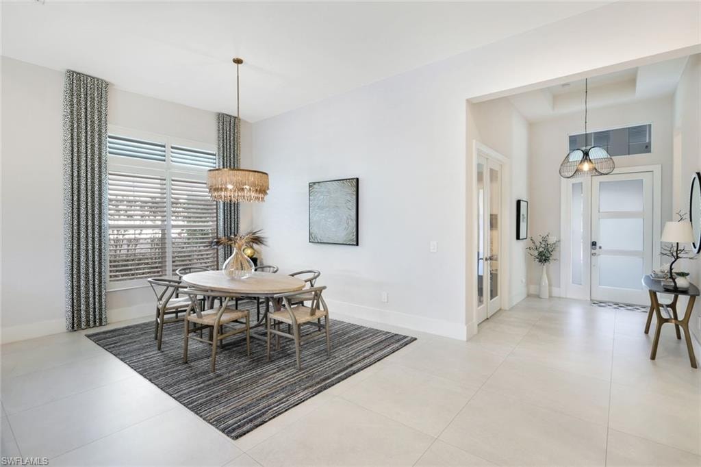 Spacious interior featuring light-toned tile flooring, tall ceilings, and an elegant chandelier