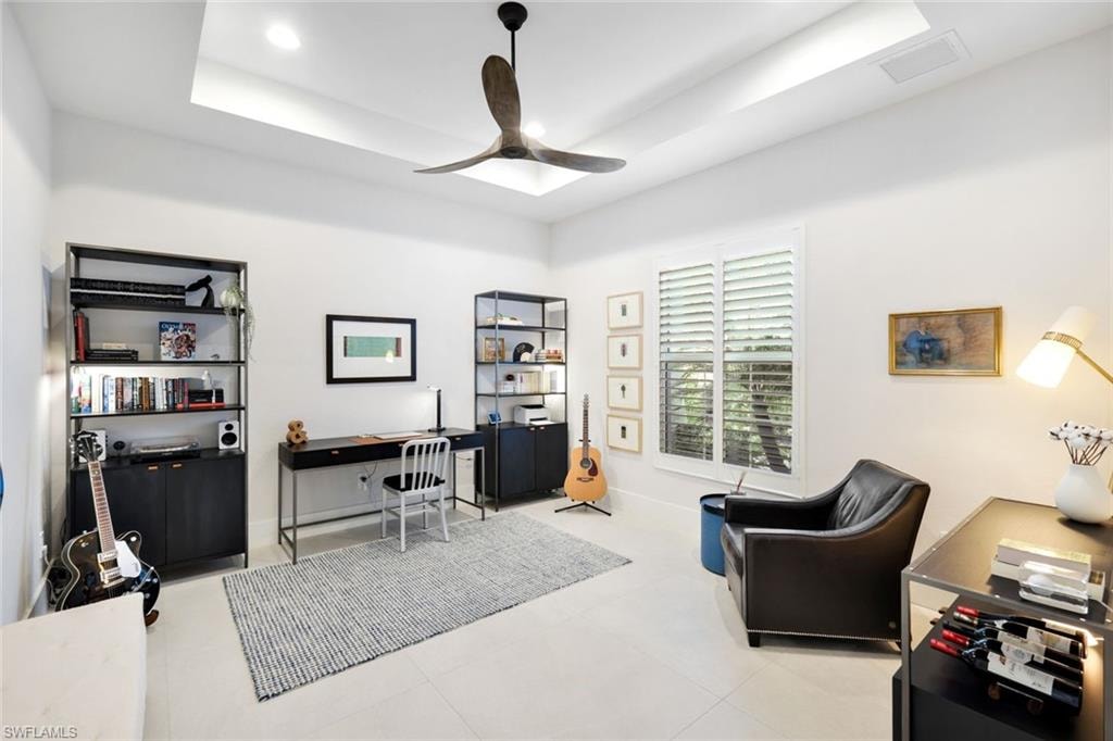 High ceilings with tray detail, recessed lighting, and a ceiling fan