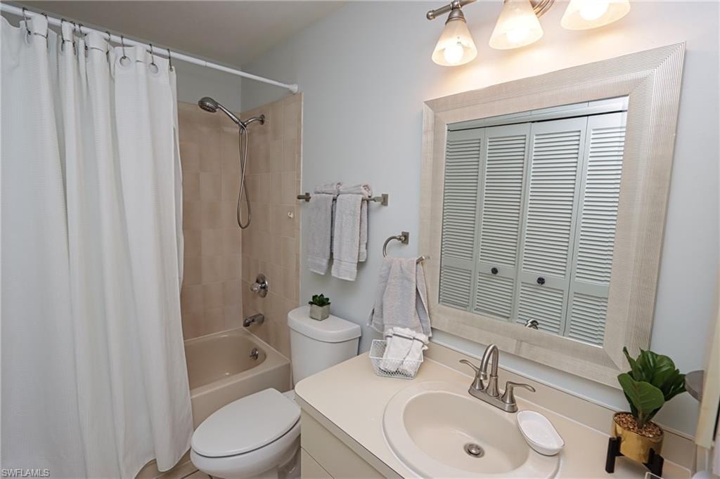 Full bathroom featuring shower / bath combination with curtain, vanity, and toilet