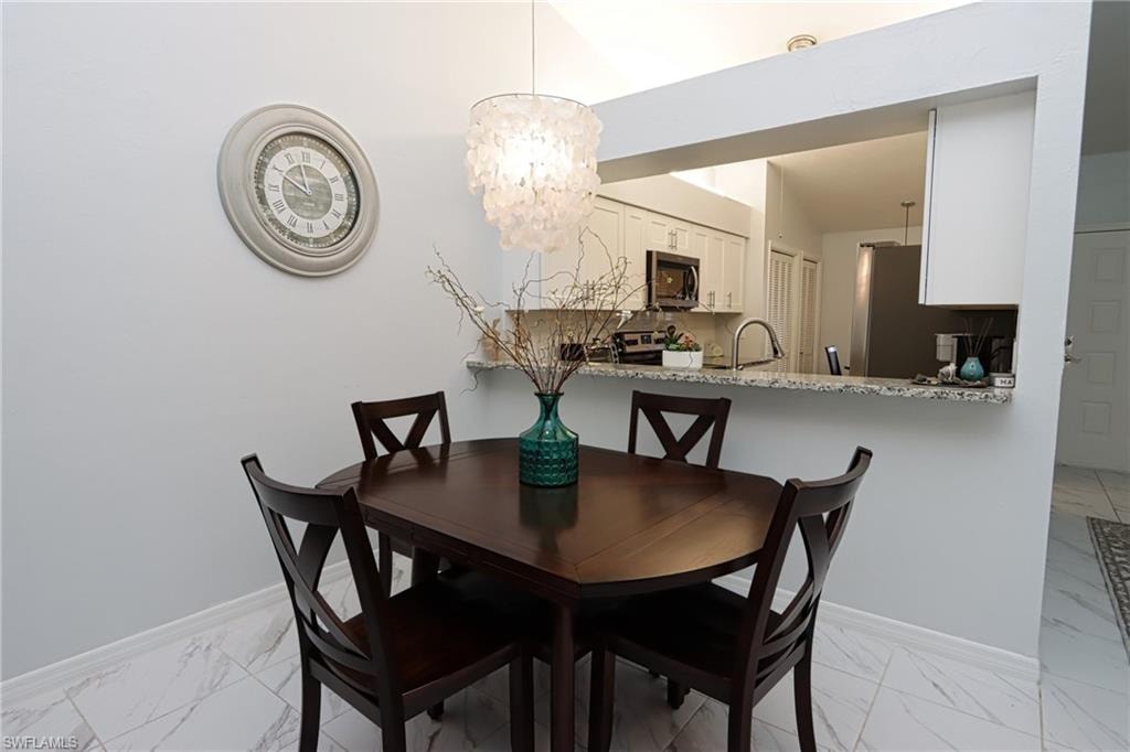 Dining space featuring vaulted ceiling, a notable chandelier, and sink