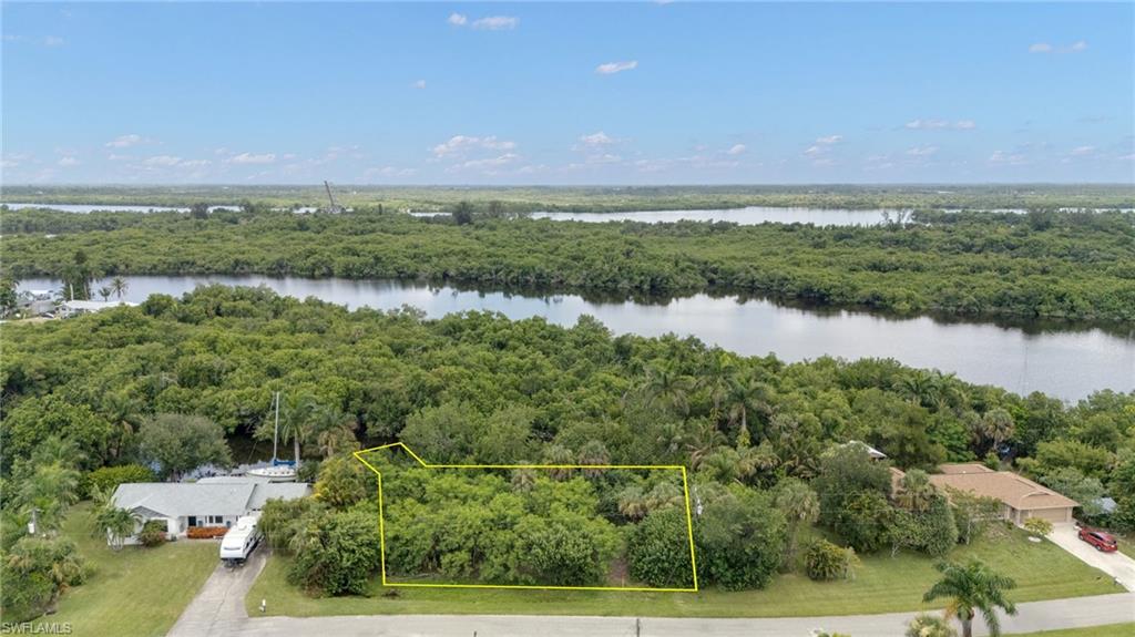 Vacant land parcel featuring mature trees, a clear boundary outline, and direct frontage on a paved street