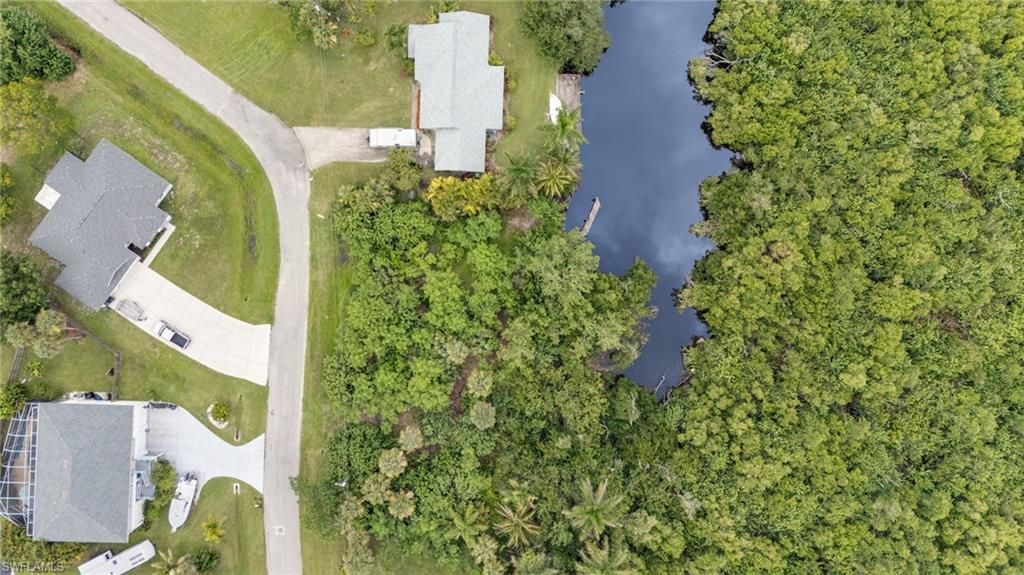 Property featuring a waterfront lot with dense natural foliage and a small dock structure