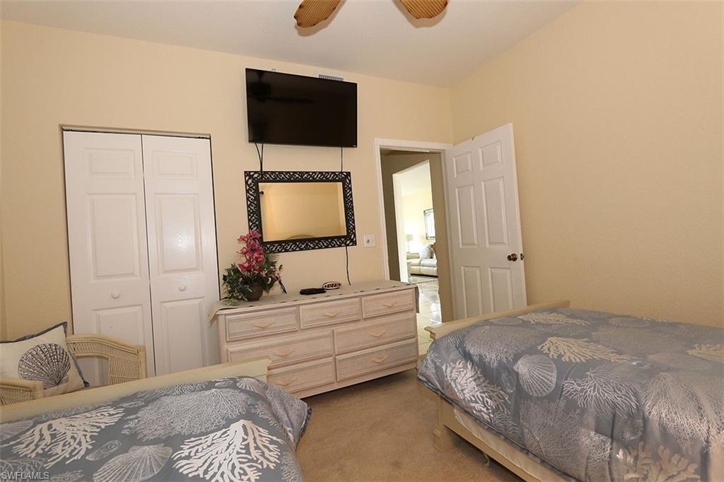 Bedroom with a closet, ceiling fan, and light colored carpet