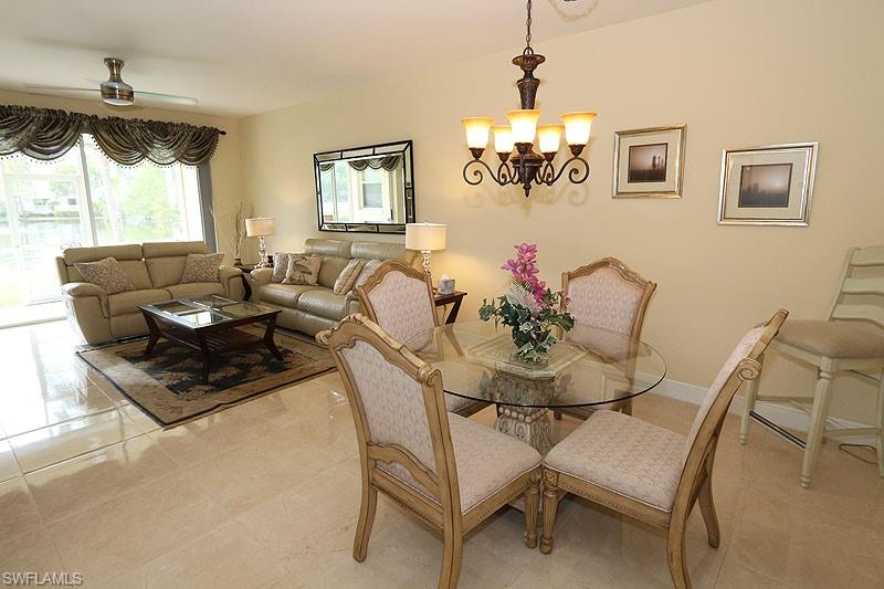 Tiled dining room with ceiling fan with notable chandelier
