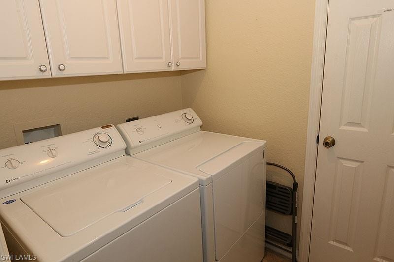 Laundry area with washer and clothes dryer, cabinets, and washer hookup