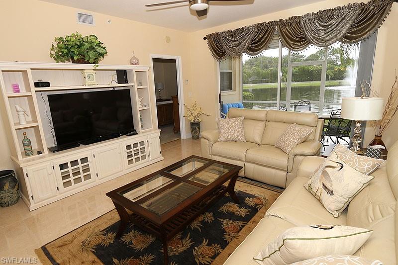 Living room featuring ceiling fan, a water view, and light tile floors