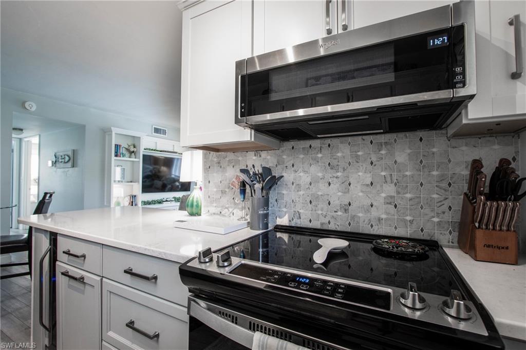 Kitchen featuring stainless steel appliances, white cabinets, hardwood / wood-style floors, and backsplash