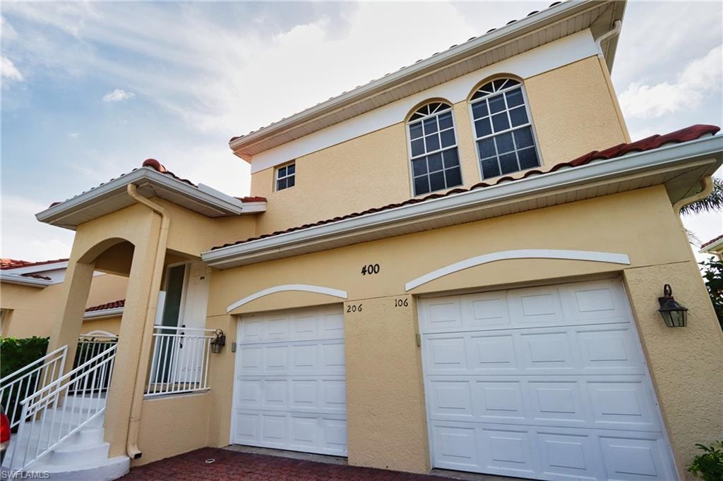 View of front of house featuring a garage, stucco siding, and a tile roof