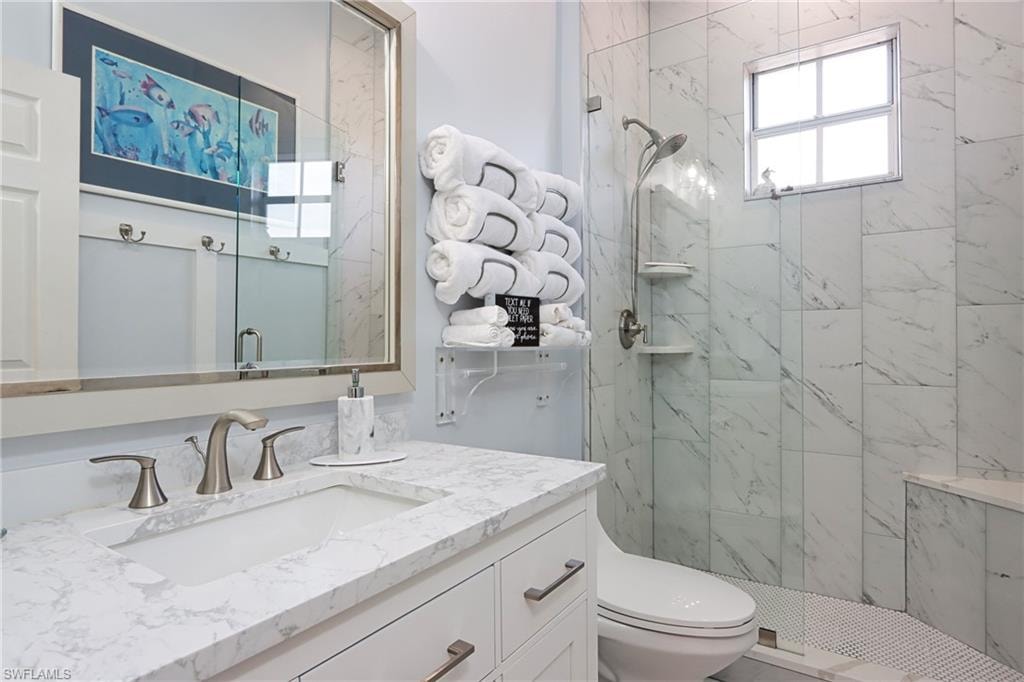 Full bath featuring vanity and a marble finish shower