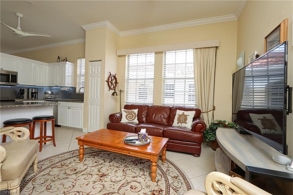 Living area featuring ornamental molding, light tile patterned floors, and ceiling fan